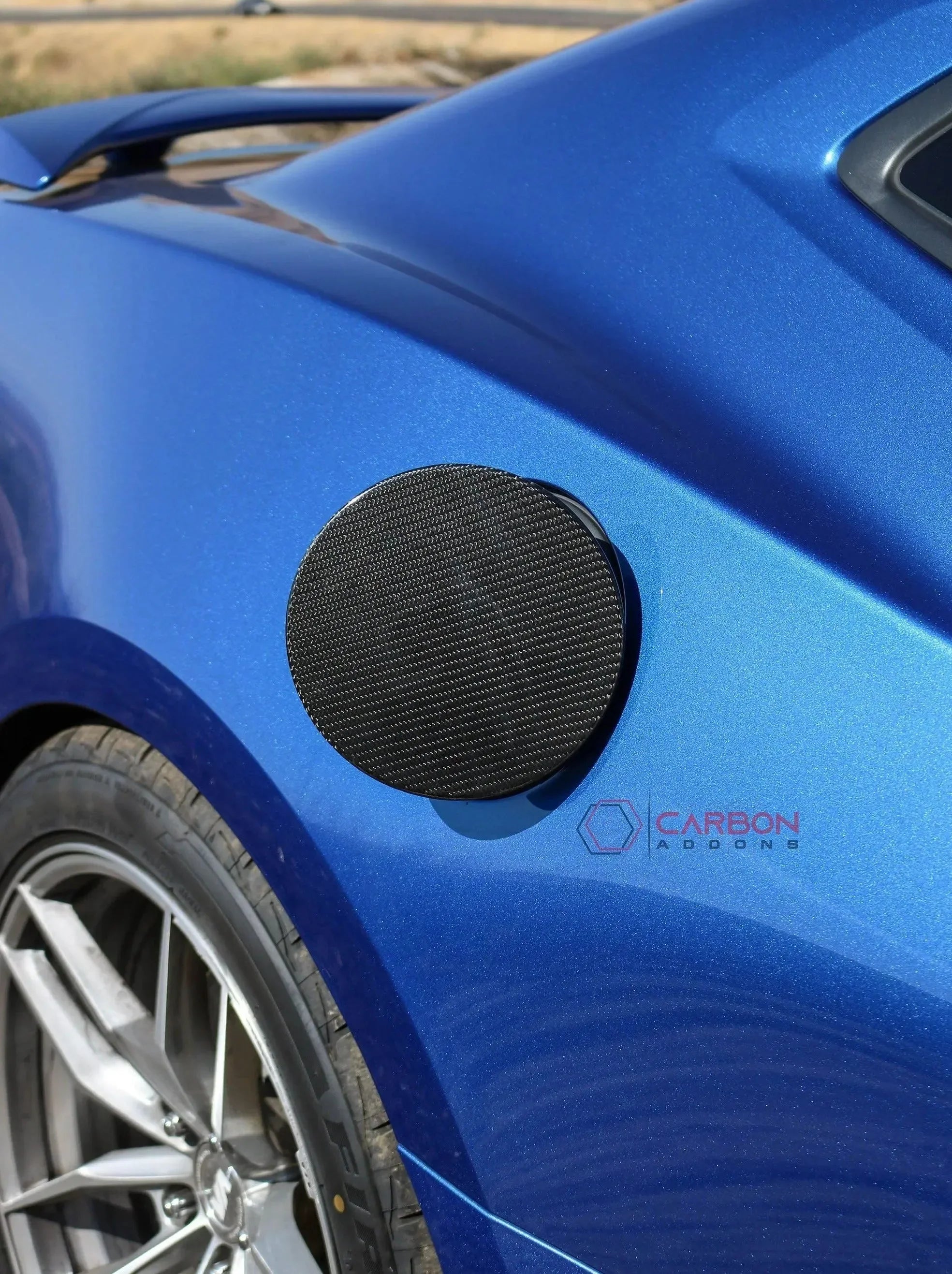 Real carbon fiber fuel door cover on blue muscle car, enhancing style for Ford Mustang or Chevy Camaro.