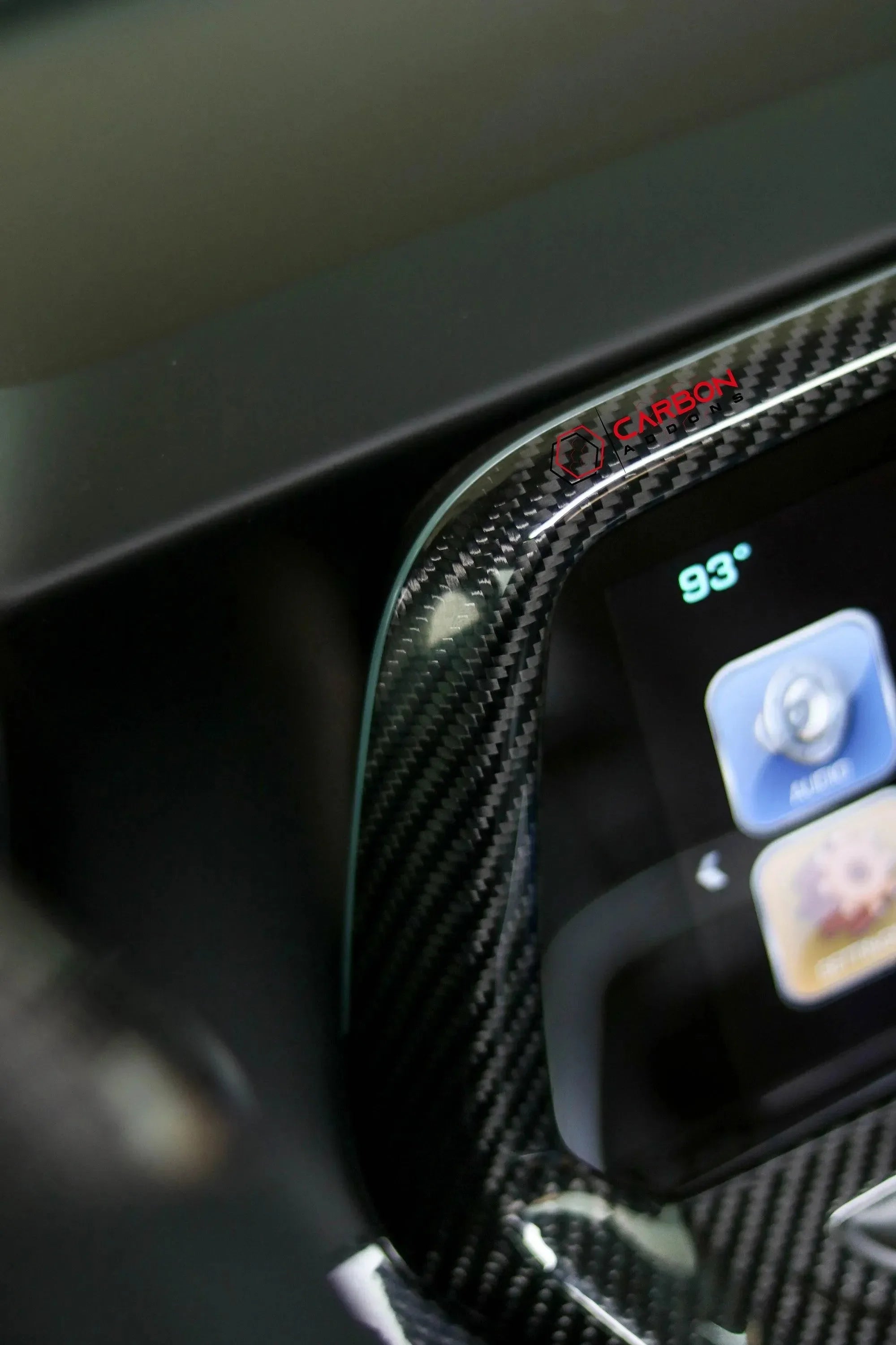 Real carbon fiber trim with Carbon Addons logo on car infotainment screen bezel