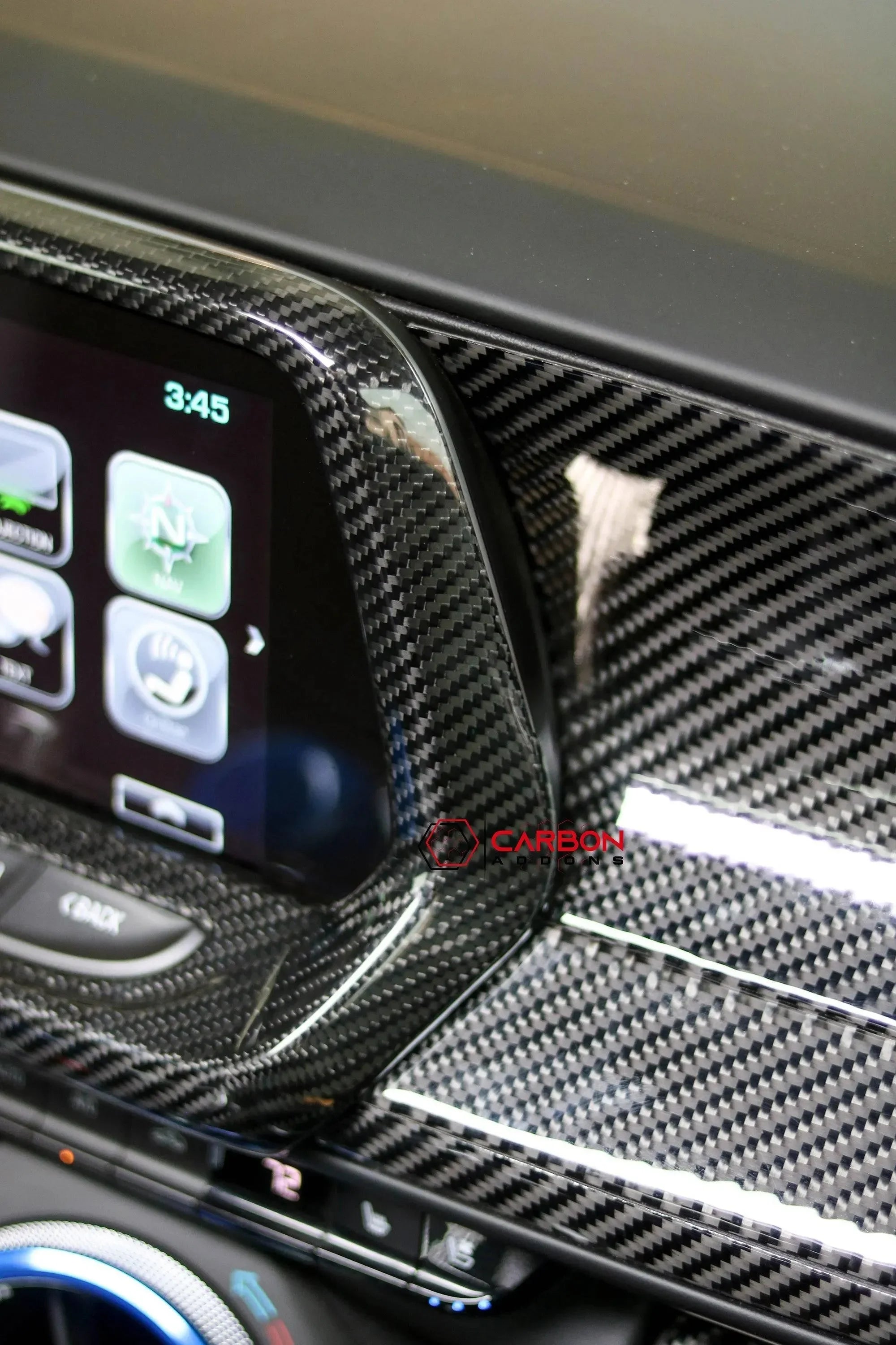 Glossy carbon fiber interior trim around car infotainment screen and dashboard controls