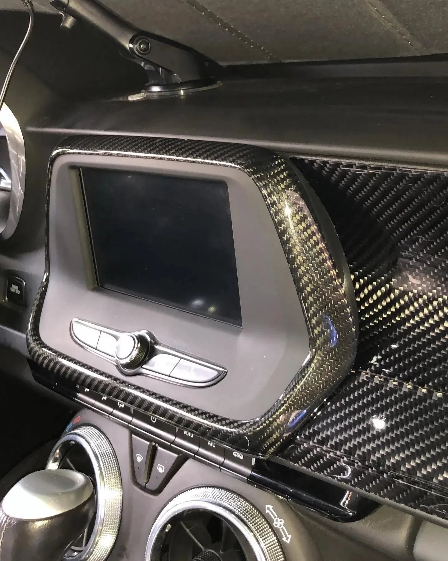 Real carbon fiber interior trim wrap on vehicle dashboard and infotainment panel