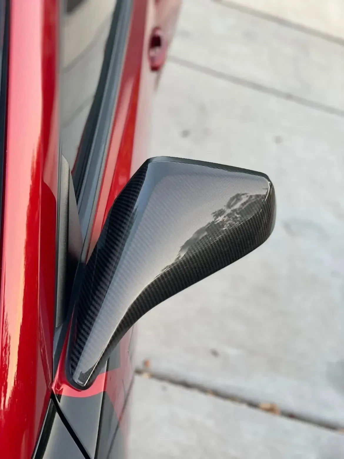 Real carbon fiber side mirror cover on red sports car, sleek exterior auto accessory