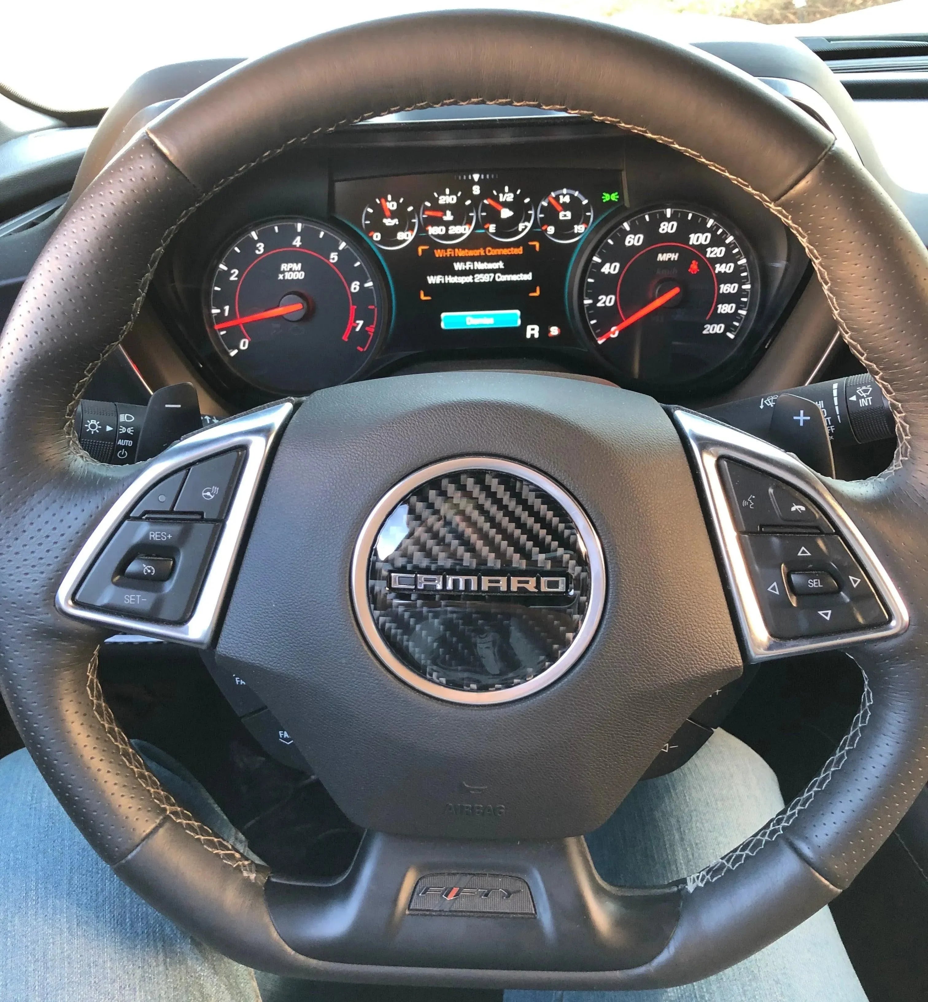 Chevy Camaro steering wheel with real carbon fiber center and leather wrap, showcasing performance gauges and controls.