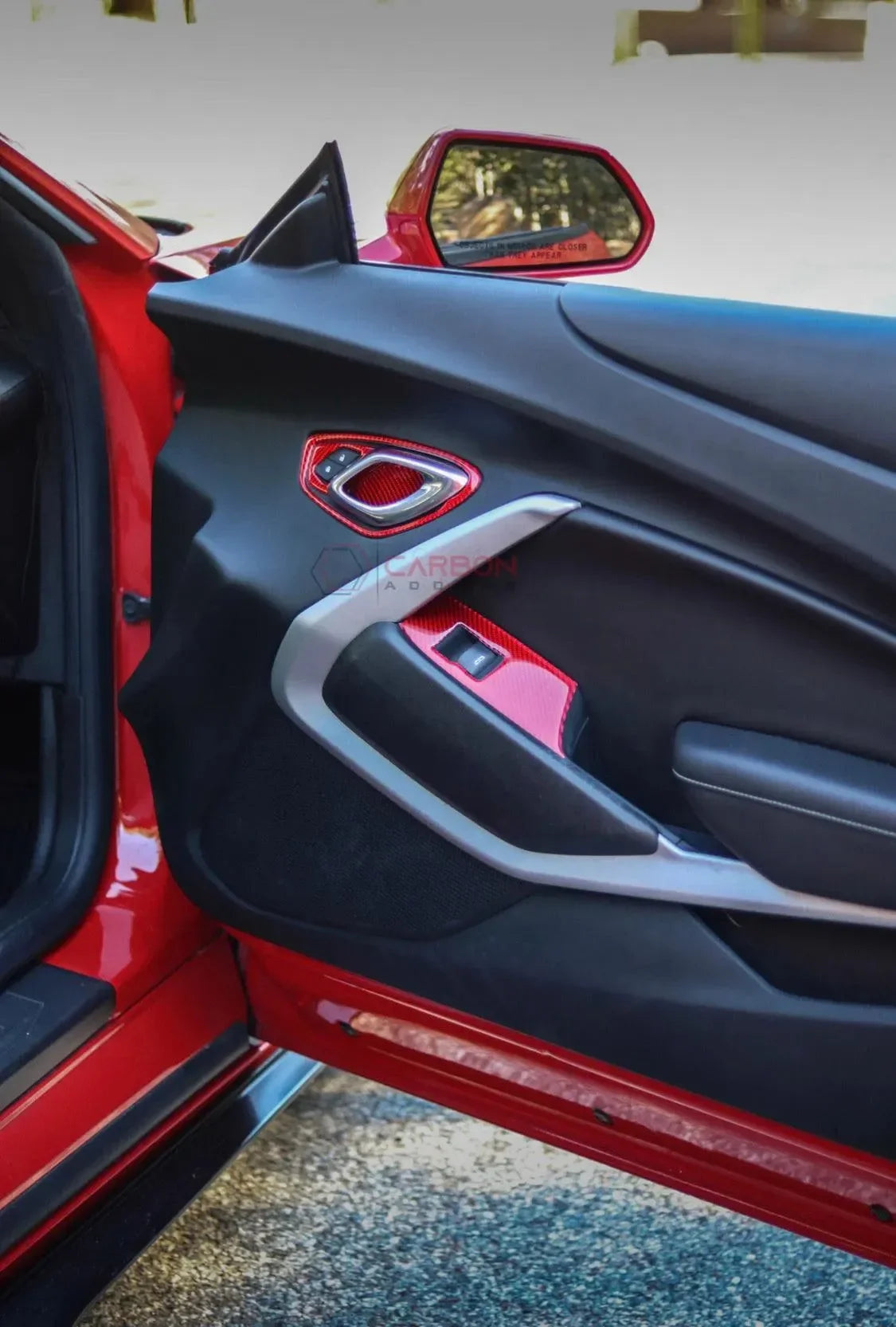 Red car door with carbon fiber accents and sleek interior trim