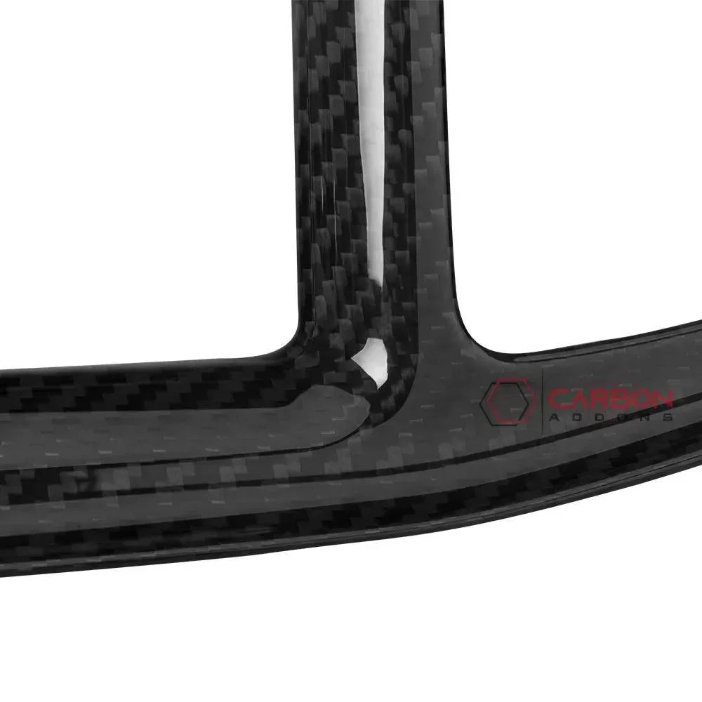 Real carbon fiber automotive trim with glossy weave pattern and branded logo detail