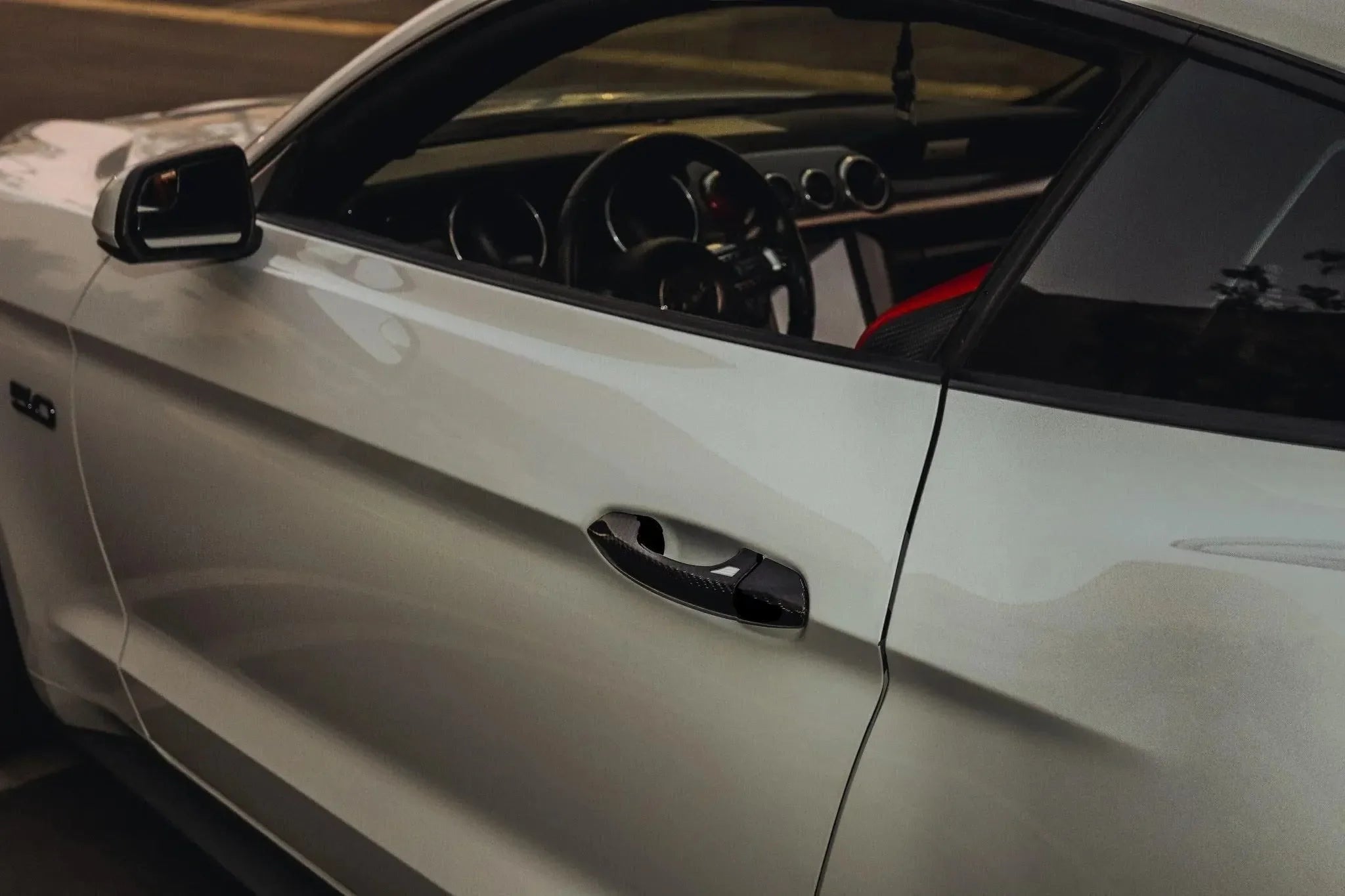 White Ford Mustang with carbon fiber door handle and interior trim, showcasing real carbon fiber automotive parts.