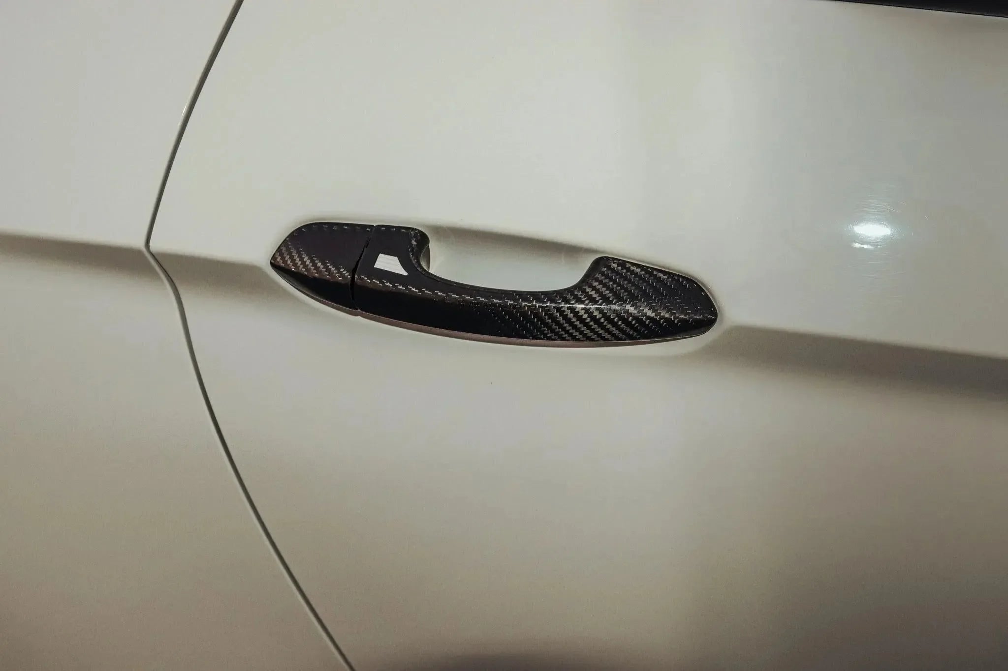 Real carbon fiber door handle cover for American vehicles, sleek black weave on white car exterior