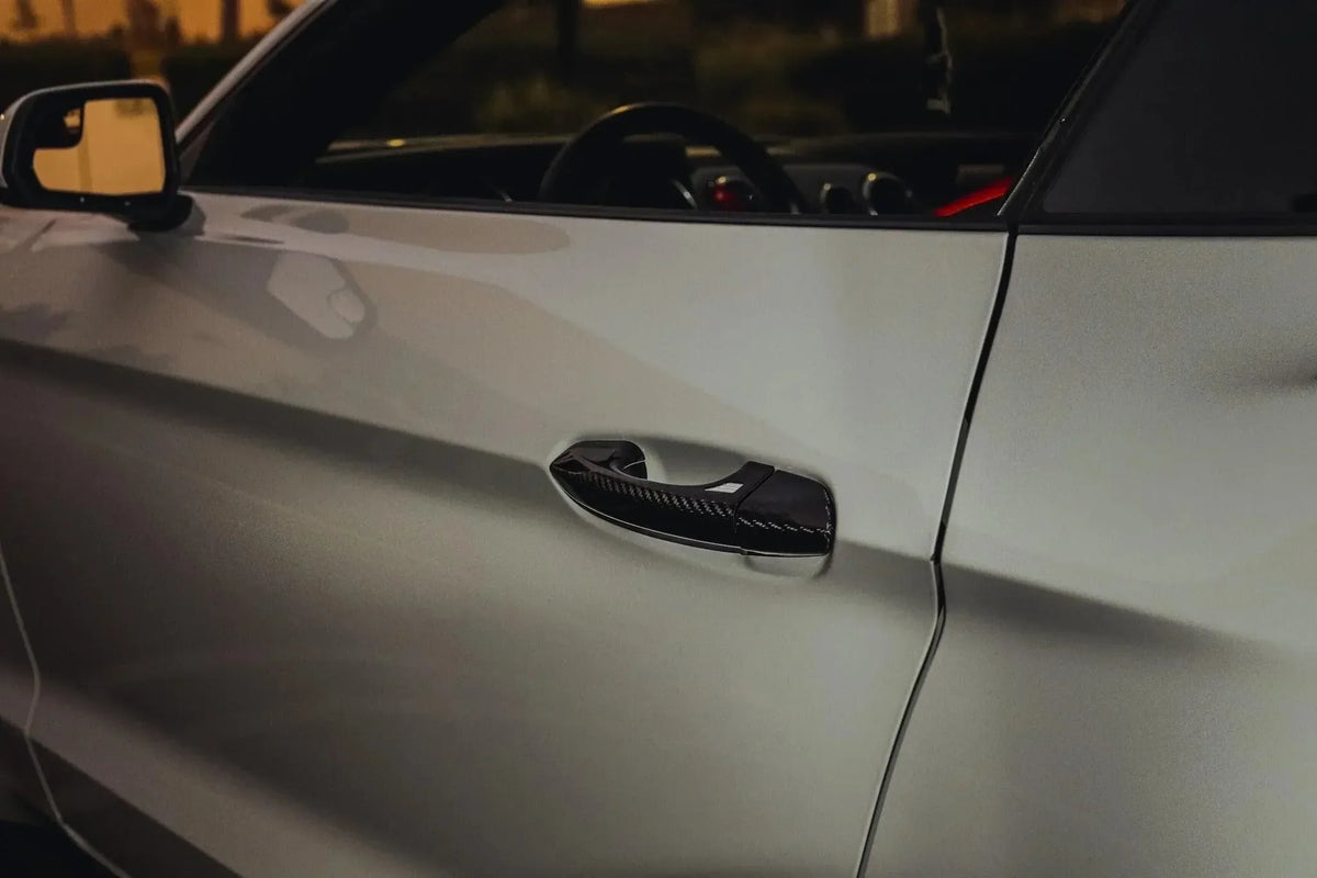 Real carbon fiber door handle cover on white sports car exterior at night