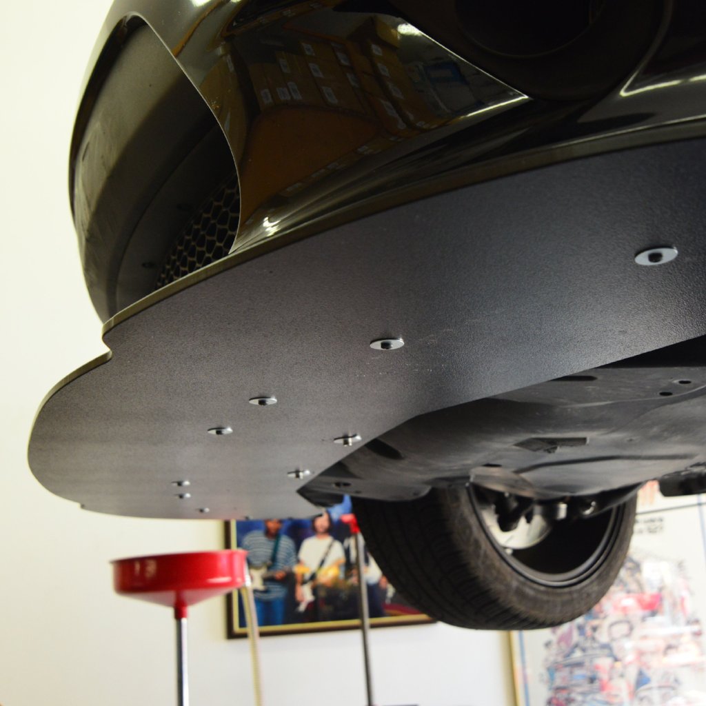 Close-up of a car's undercarriage with a blurred indoor background