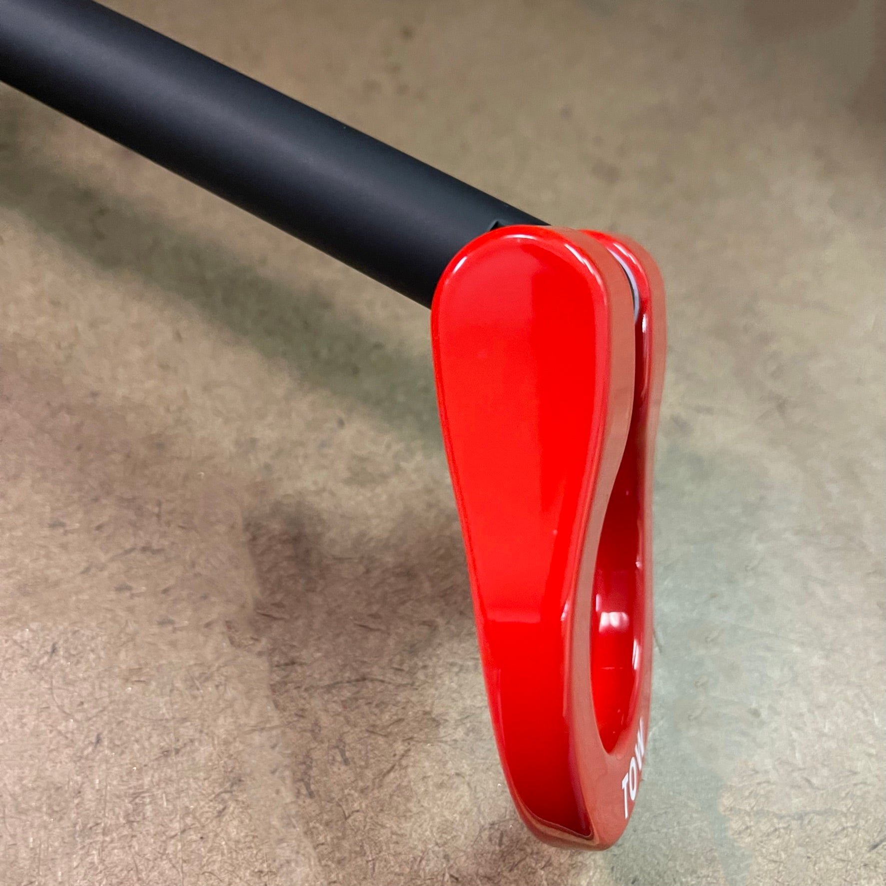 Close-up of a red scooter kickstand on a gray surface