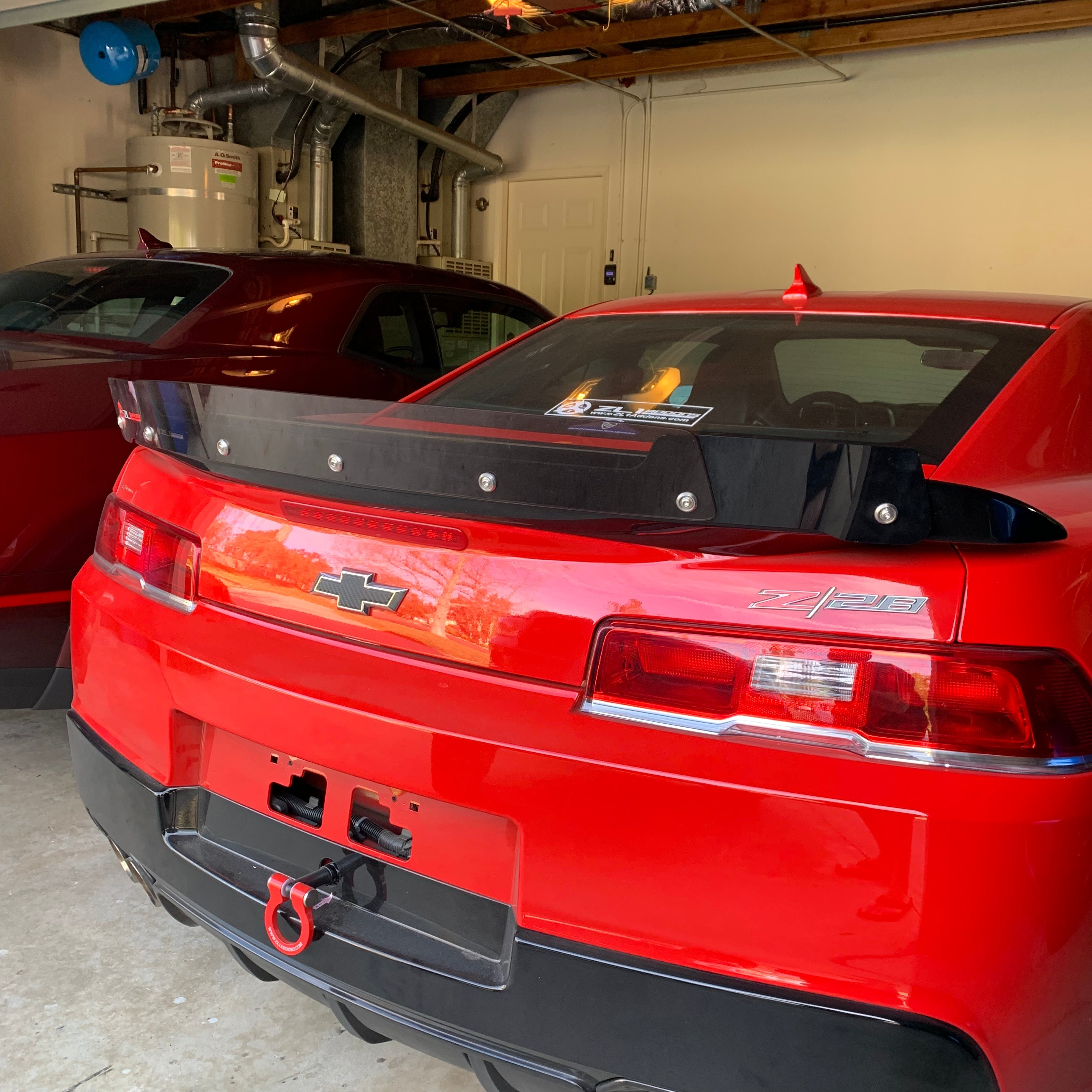Red car with a black spoiler in a garage setting